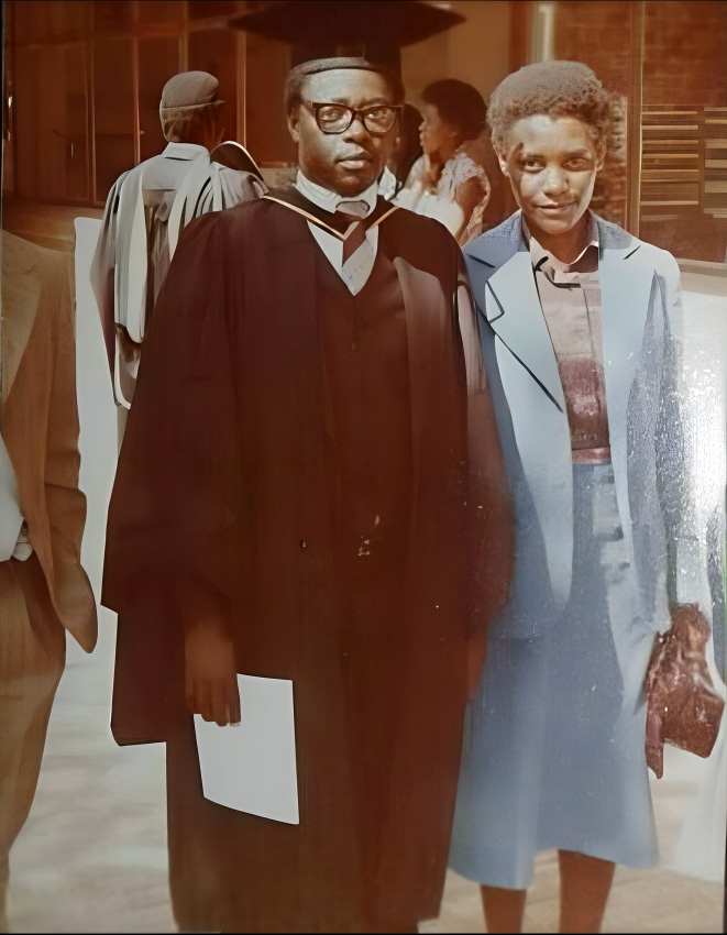 Nicholas and Cecilia Shoko. Nicholas wearing a graduation grown. Cecilia wearing a blue suit. Smiling at the camera